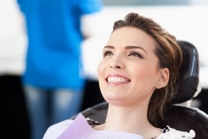 Smiling Female in Dental Chair Preparing for Examination