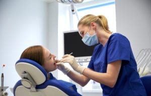 female dentist checking patient girl teeth