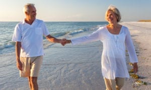 Mature Couple holding hands while walking on the beach